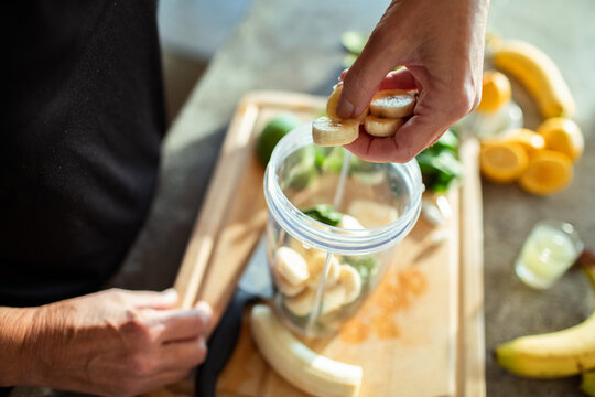 Body positive senior woman making healthy smoothie in modern kitchen