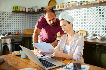 Couple reviewing bills and finances together at kitchen table