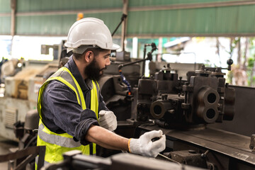 Male factory worker working with heavy machinery in industrial factory