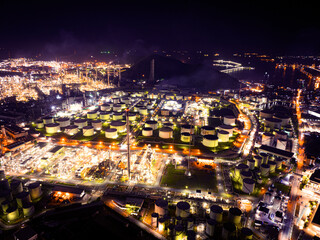 Factory - oil and gas industry, Oil factory, A huge oil refinery with metal structures, pipes and distillation of the complex with burning lights at dusk, Aerial view, logistics park