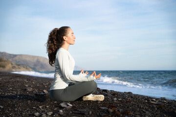 Young woman doing yoga meditation outdoors. Side view of a girl practicing yoga and meditation...