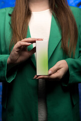 Hands presenting a rectangular box with a green and white gradient, held by a person in a green...