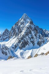 Fototapeta premium Majestic Snow-Capped Mountain Against Clear Blue Sky in Winter Wonderland Landscape