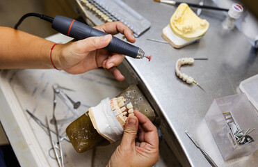 Dental technician shaping prosthetic teeth with rotary tool