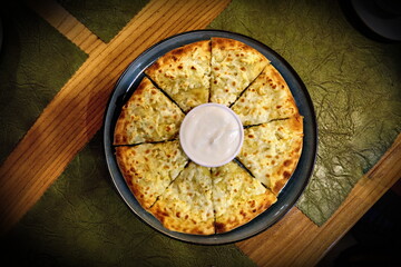 Megruli khachapuri with a cup of sour cream in the middle.
