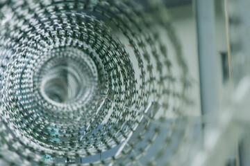 A close-up of a razor wire coil, creating an abstract geometric pattern. The intricate design of...
