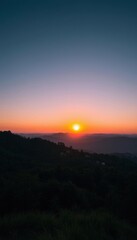 Obraz premium a sunset over a mountain with a few trees