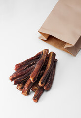 A natural chewable treat for dogs with a paper bag on a white background. A healthy treat for pets of all breeds and ages 