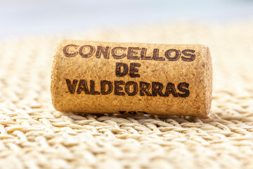 Close-up of a wine cork with 'Concello De Valdeorras' branding, set against a textured wooden background, highlighting wine culture and rustic design elements.