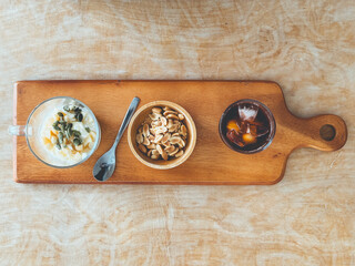 Healthy snack set of beans seeds yogurt and iced coffee on wooden plate.