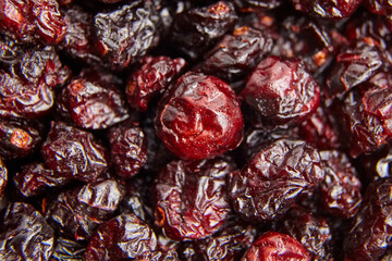 Macro view of dried cranberries showcasing their wrinkled texture and rich red color. Shiny surfaces reflect light, highlighting their natural sweetness