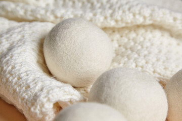 Close-up of wool dryer balls resting on a cozy white knitted fabric. Eco-friendly, reusable laundry accessory designed for static reduction and gentle drying