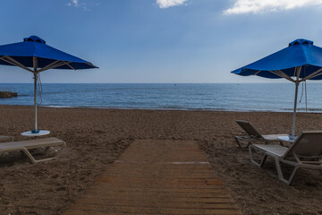Beach by the sea on the island of Rhodes in Greece. Parasols and sunbeds on the beach.