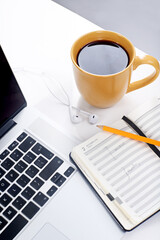 Closeup, laptop and coffee with notebook, internet and network with connection. Empty, computer and equipment with espresso, keyboard and journal with diary, pencil and organized with technology