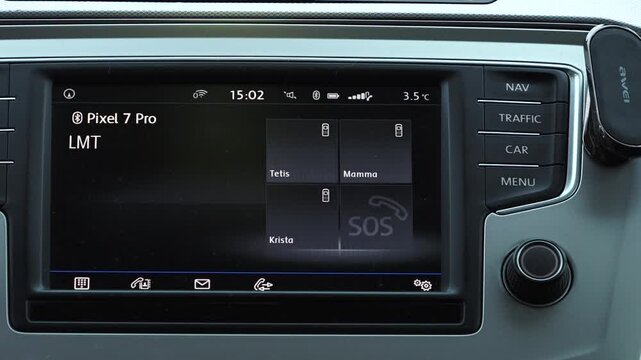 Valmiera, Latvia - November 28, 2024 - A close-up of a car infotainment system showing a connected smartphone, contact options, and an SOS emergency button, highlighting modern technology.
