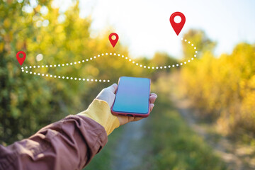 Woman standing in middle of forest, using navigation app on smartphone, following route with help...