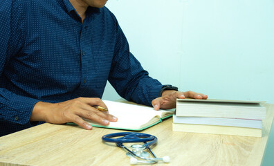 Doctor is documenting a patient's information. The physician, in the white medical coat is filling out a medical record form during a consultation in the clinic.