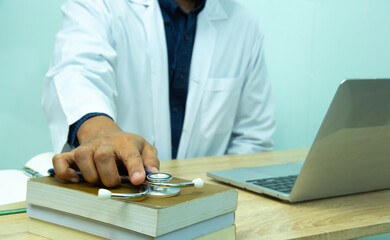 computer notebook and medical text book at desk in the hospital. Medical concept