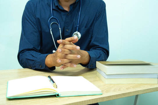 Doctor is documenting a patient's information. The physician, in the white medical coat is filling out a medical record form during a consultation in the clinic.