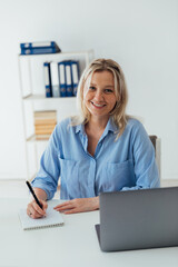 woman blonde with laptop smiling in office