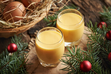 Two glasses of Eiecognac with fresh eggs in a basket and Christmas decoration