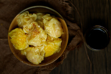 A bowl of steaming, golden dumplings, garnished with green onions.