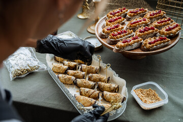 An individual wearing black gloves meticulously prepares various foods on a spotless table, ensuring careful arrangement of all crucial ingredients for the meal they are about to create
