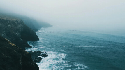 Misty coastal landscape with gentle waves lapping against rocky shore, creating serene atmosphere. fog adds mysterious touch to tranquil scene