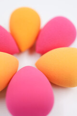 pink and orange Cosmetic sponges on light wooden background, close up