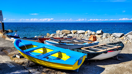 Several traditional colorful Italian fishing boats on the Mediterranean beach in Pomonte, on Elba Island, Italy. In the background - the blue sea.