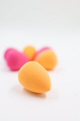 pink and orange Cosmetic sponges on light wooden background, close up