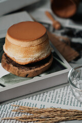 A delicate, round cake with a glossy brown top, resting on a wooden plate.