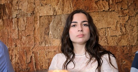 Young woman posing confidently in a cozy restaurant setting. Portrait of confident young woman in stylish restaurant, radiating elegance and charm during casual gathering. Beautiful and young woman