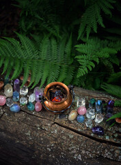 colorful gemstone crystals and witch copper cauldron in forest, natural background. occult esoteric...