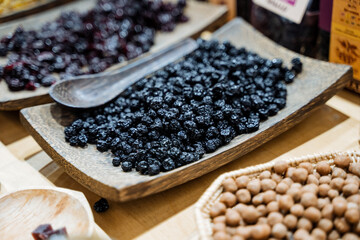 On the wooden table, there rests a charming wooden bowl that is generously filled with plump, juicy blueberries, accompanied by a spoon ready for enjoying this delicious treat