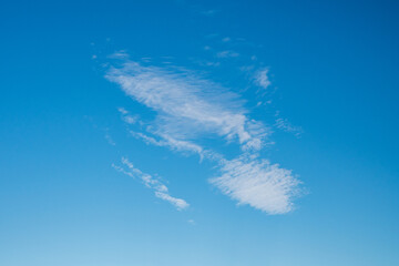 Feine weiße Wolken vor einem tiefblauen Himmel als Hintergrund