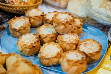 On the surface of a table, there is a blue plate that is generously topped with an assortment of delightful pastries, creating an inviting and tempting treat for everyone nearby