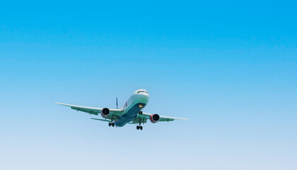 The plane in the sky goes to the landing on runway against with clear blue sky in sunny day....