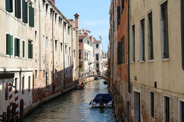 Side view of empty narrow water canal between residential brick buildings in a sunny summer day in Venice, Italy. Soft focus. Copy space. Old town Italian architecture. Vacation in Europe theme.