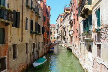 Side view of empty narrow water canal between residential brick buildings in a sunny summer day in Venice, Italy. Soft focus. Copy space. Old town Italian architecture. Vacation in Europe theme.