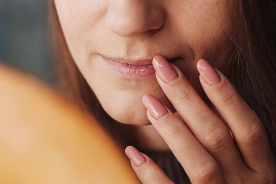 Woman applying petrolatum on lips. Dry mouth care for winter season. Closeup of lips with finger applying lip salve. Beauty and skincare routine for moisturized lips.
