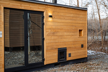 This charming wooden house, featuring a large glass door, warmly invites natural light to flow inside, offering a serene beauty for those who truly appreciate the wonders of nature