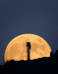 Full beaver moonrise behind the watchtower. The moon is very large compared to the tower and yellow in color. © Ricard