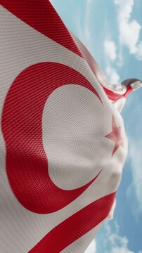 Wavy flag of Northern Cyprus blowing in the wind in slow motion. Waving official North Cypriot flag team symbol abstract vertical background. Blue sky with clouds. World countries flying flags concept