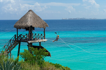 Vacation day on a tropical island in mexico with people on the zipline over the sea, extreme activities in Isla Mujeres
