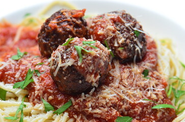 A closeup shot of a Spaghetti Meatballs dish made from Tomato sauce and drizzled with freshly chopped Parsley.