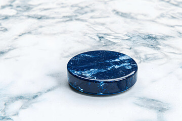 Round blue stone resting on a textured marble surface, showcasing natural patterns and colors for artistic displays and design projects