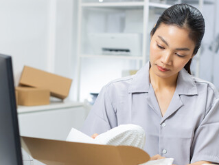 Online store shop preparing a product packing into the box for delivery.
Asian businesswoman seller packing a product parcel box for ship to the customer. Working online selling and e-commerce.