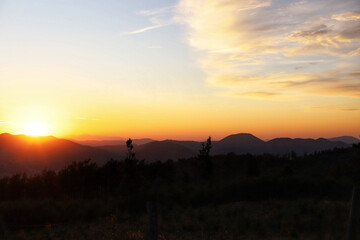 A breathtaking sunset view from the mountain peak in the Owl Mountains in Lower Silesia, Poland, with vibrant colors illuminating the sky and landscape below.