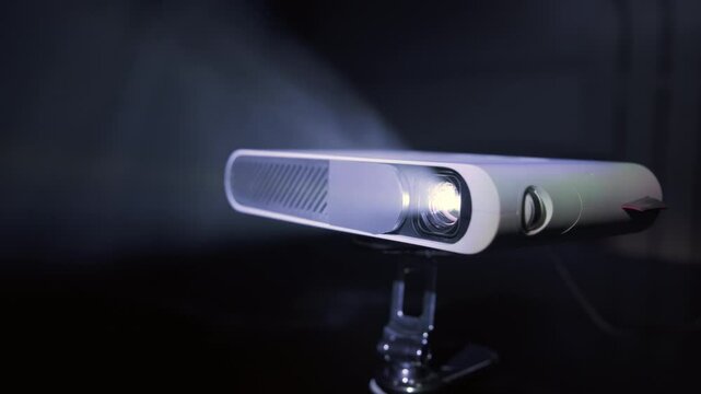 Modern pocket video projector showing film emitting beam of light.